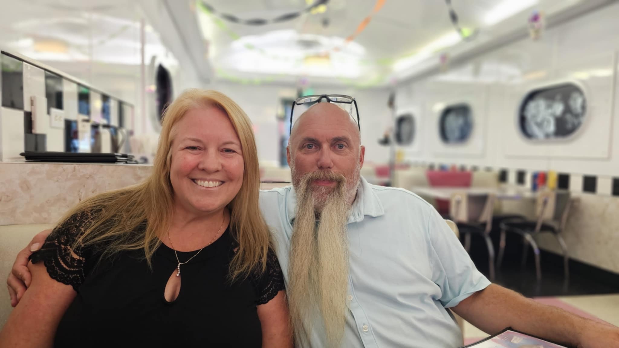 Joe and Tina at a classic 50s retro diner in San Diego with black and white checkerboard decor and rock-n-roll portraits on the wall
