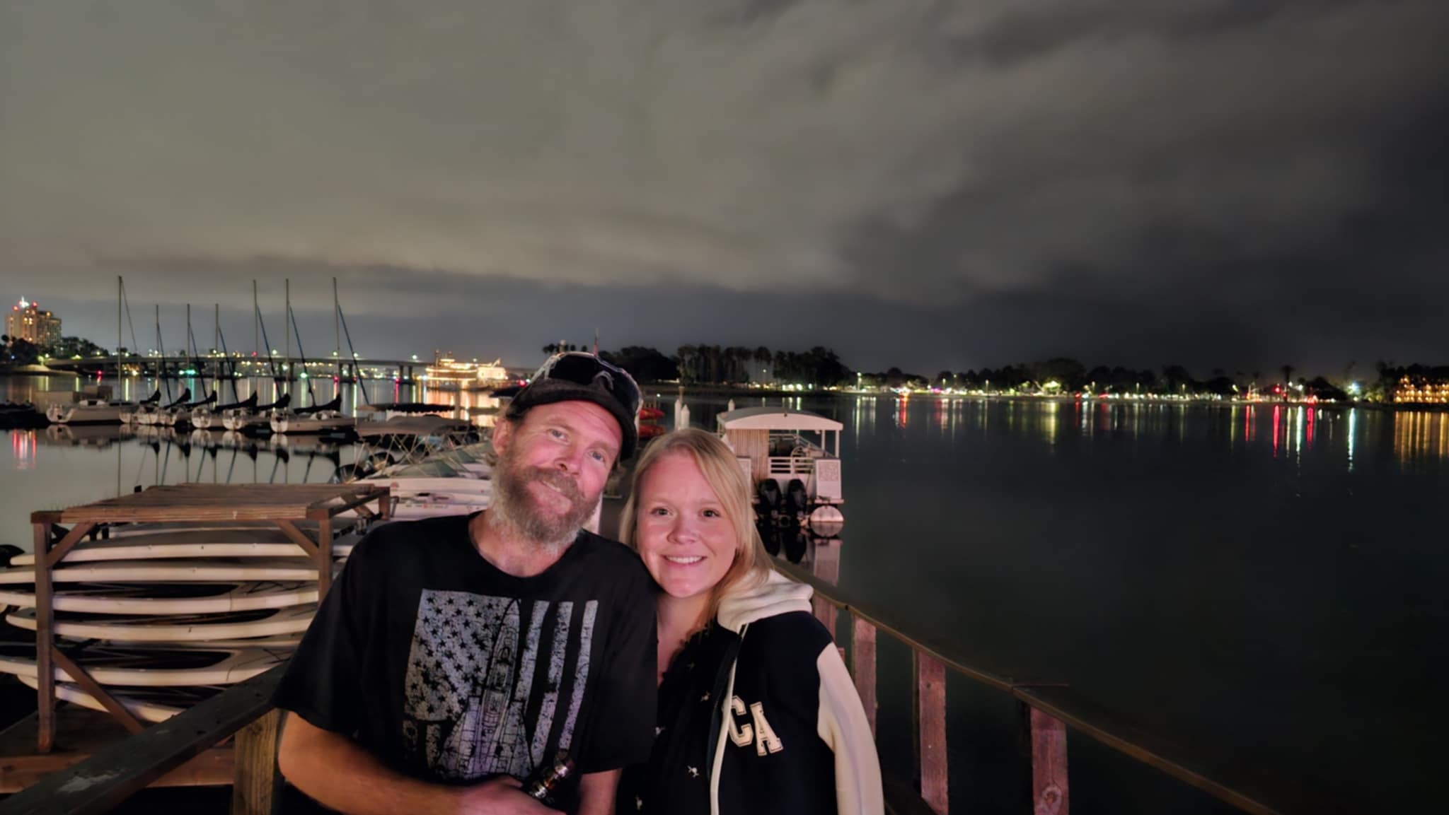 Shelby and Ben on the Mission Bay waterfront dock at night with sailboats and city lights reflecting on the water