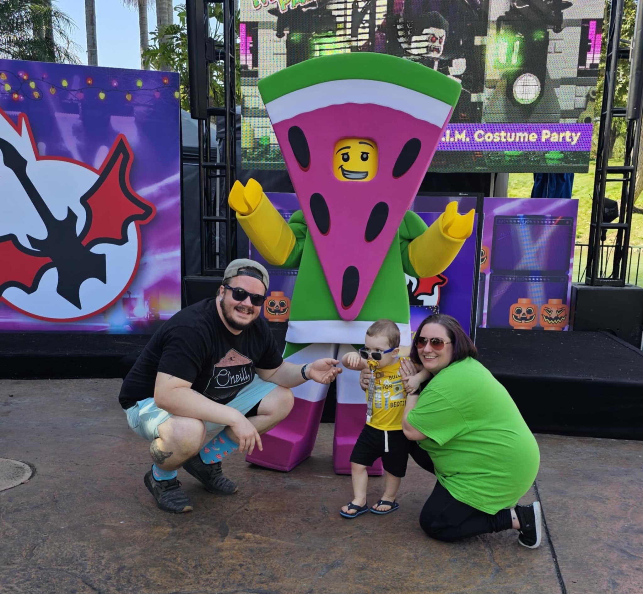 Josh, Amanda, and Ronald posing with the LEGO Watermelon character at the Monster Party costume event at LEGOLAND California