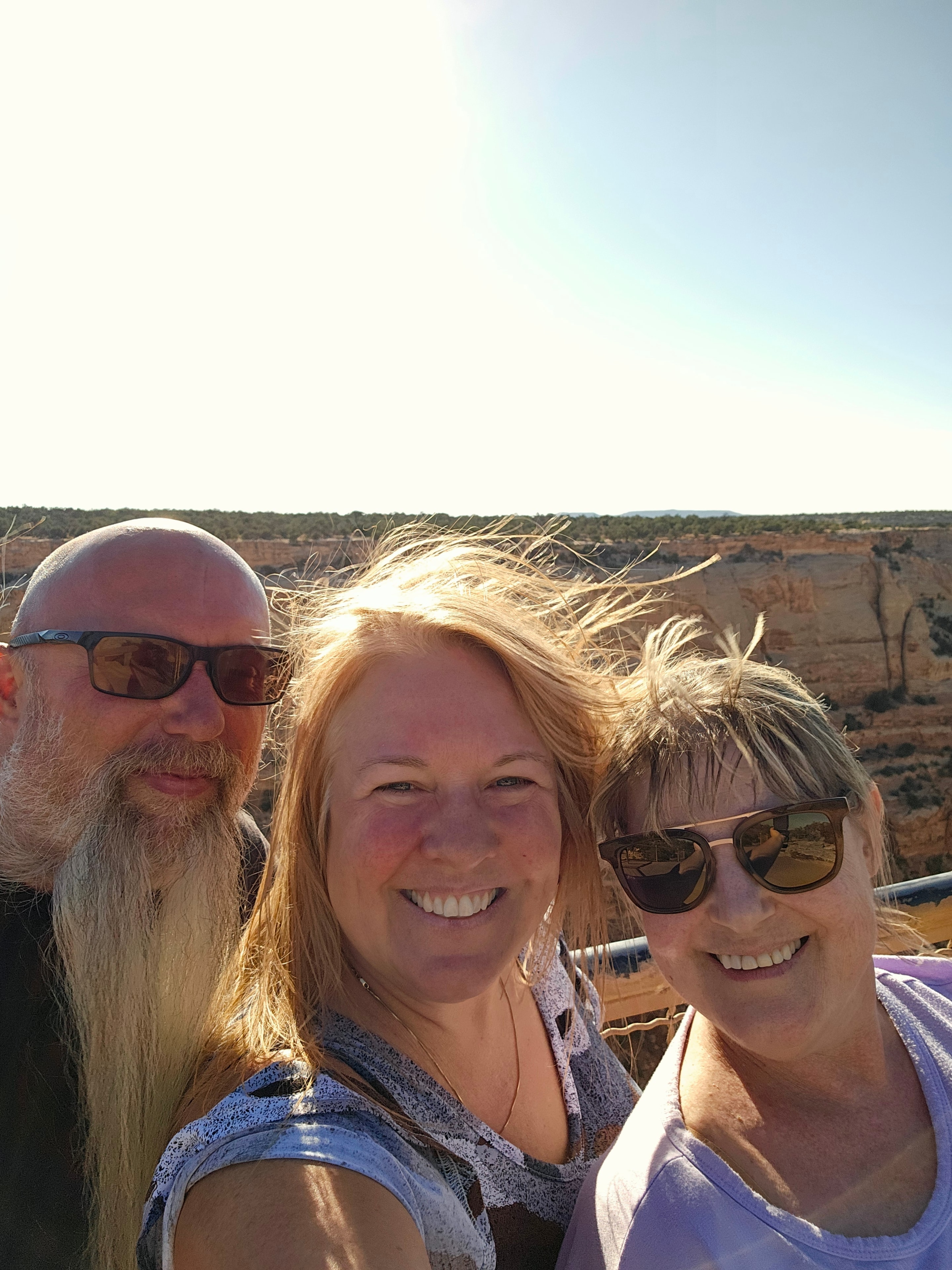 Joe, Tina, and Cynthia selfie on the canyon rim at Colorado National Monument — golden backlight, canyon walls behind — LOVING LIFE HAVING FUN Brinkley Z3400