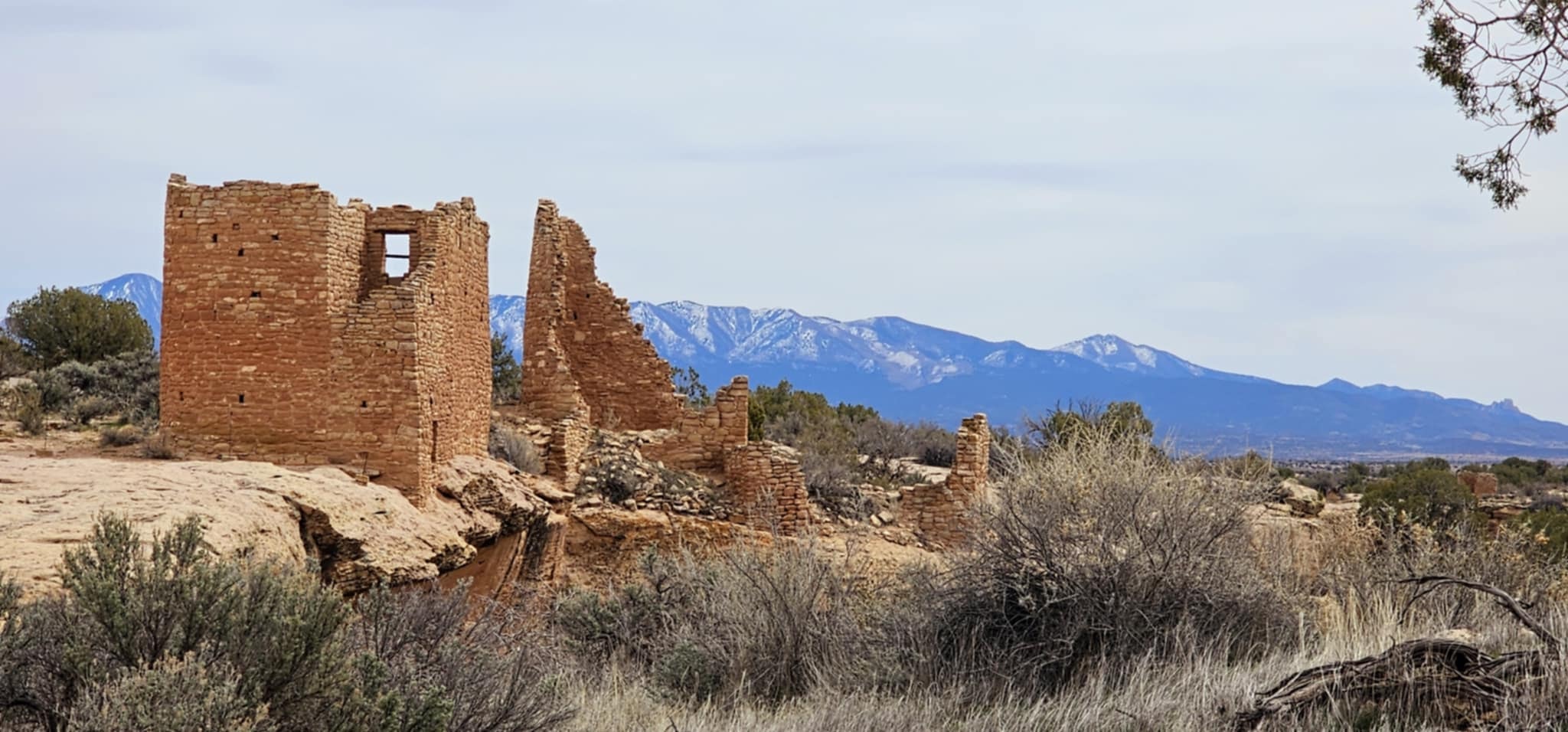 Hovenweep Castle ruins with snow-capped mountains rising behind them across the high desert