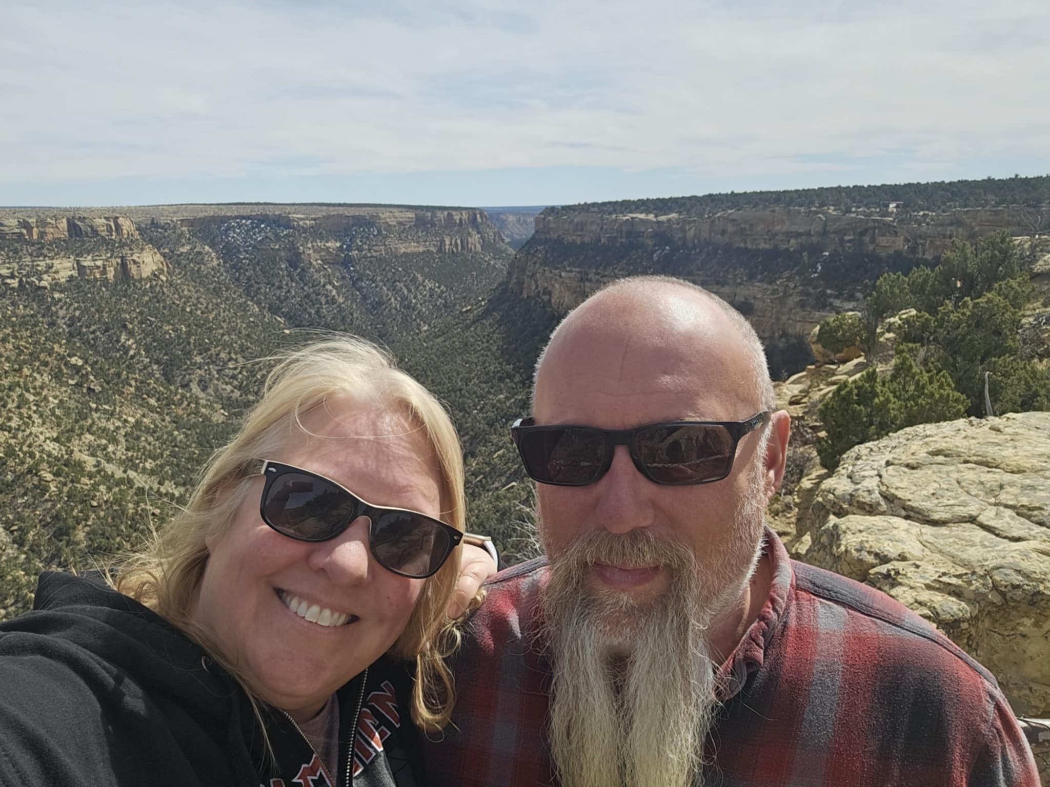 Joe and Tina selfie at a Mesa Verde canyon overlook with deep sandstone canyon walls stretching behind them