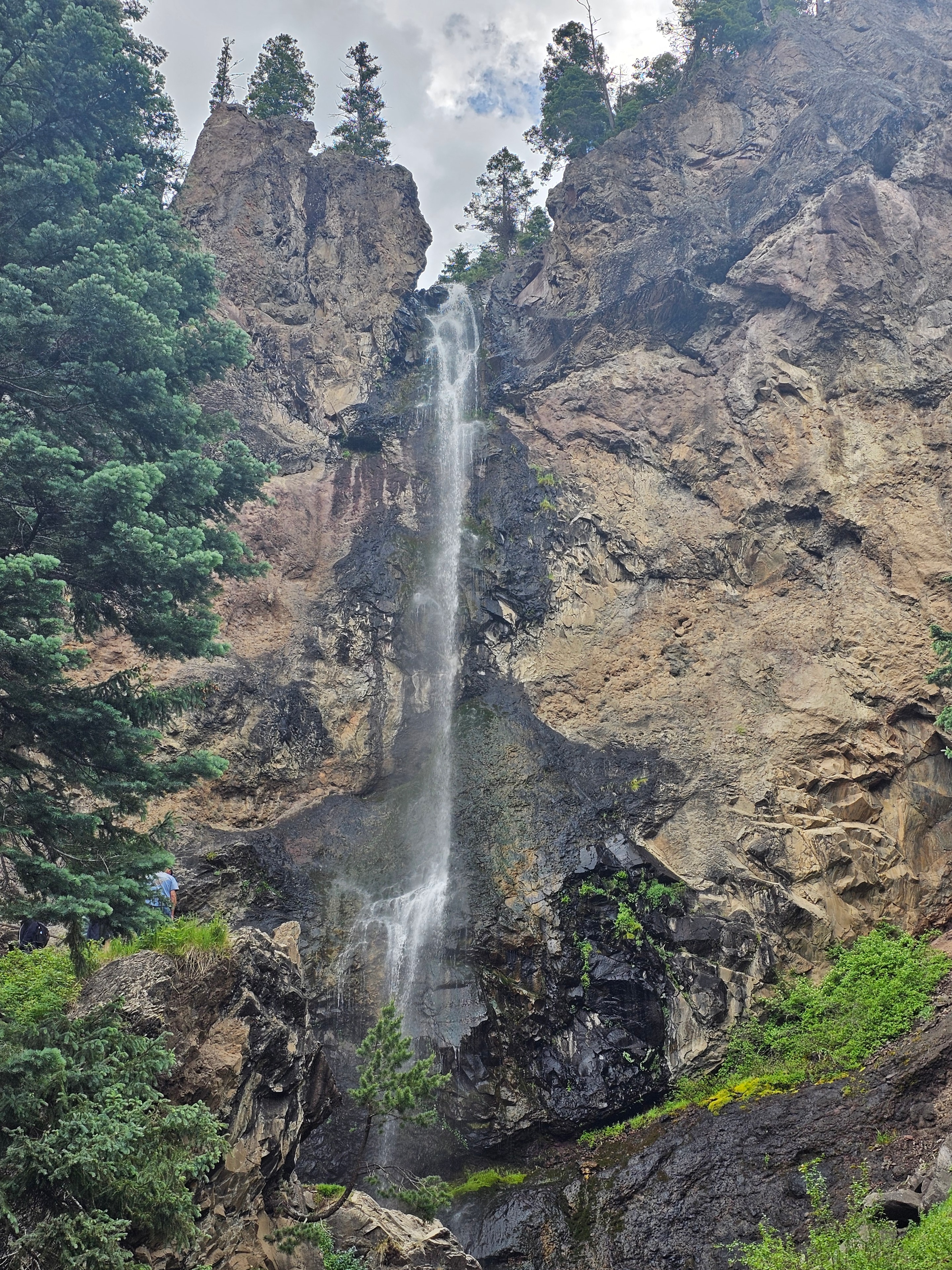 Treasure Falls wide shot — full cliff face with cascading water, spruce trees below, Wolf Creek Pass, Colorado — LOVING LIFE HAVING FUN Brinkley Z3400