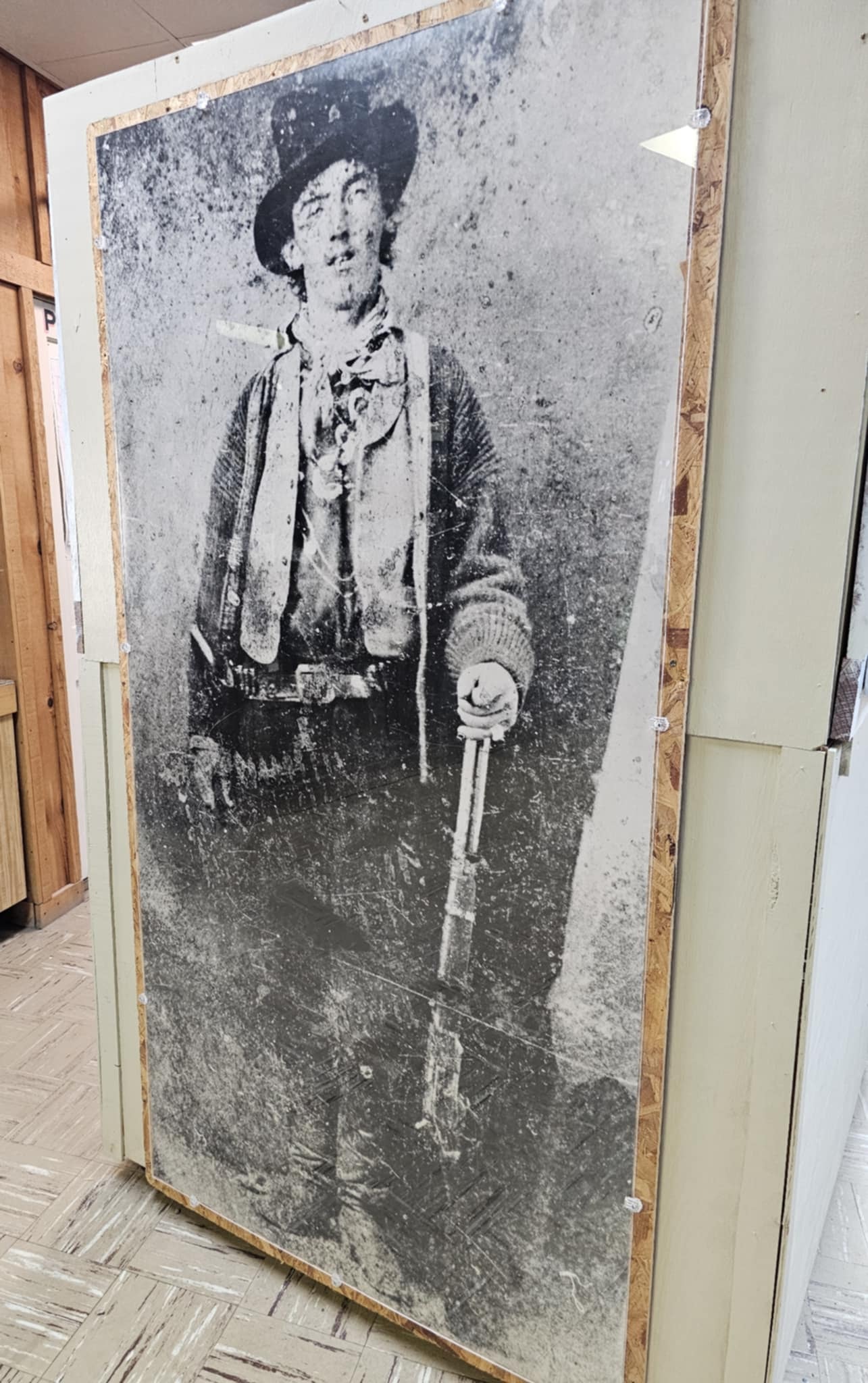 Massive black and white enlargement of the famous Billy the Kid tintype photograph displayed inside the Billy the Kid Museum in Fort Sumner, showing the young outlaw in full standing pose with his Winchester rifle