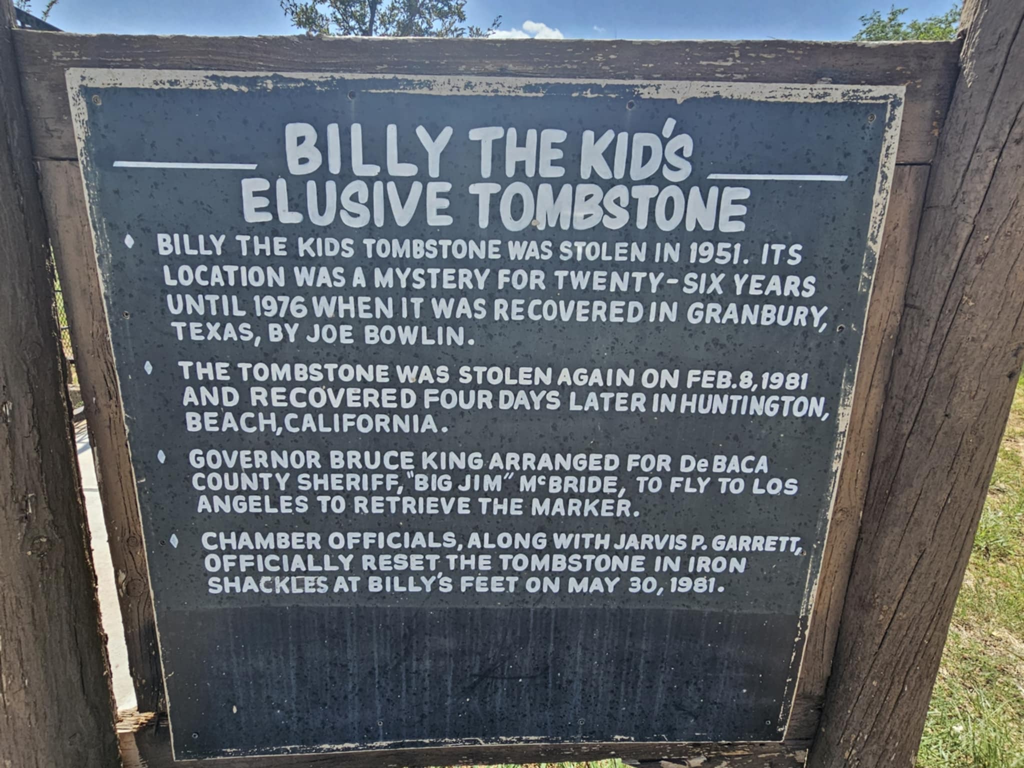 Historical marker titled "Billy the Kid's Elusive Tombstone" detailing how the tombstone was stolen in 1951, recovered in Granbury Texas in 1976, stolen again in 1981, and finally secured in iron shackles at Billy's feet on May 30, 1981