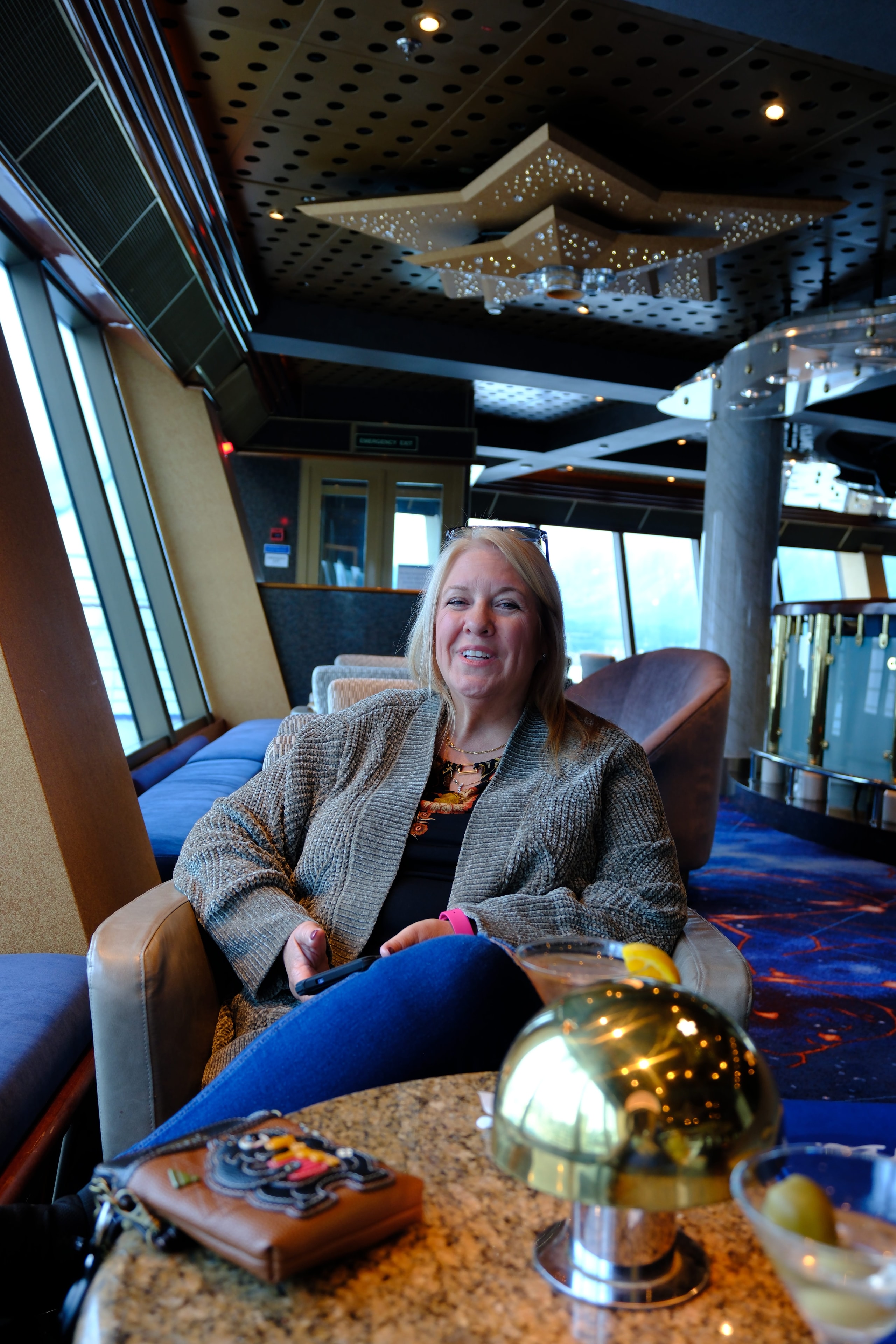 Tina sitting in Skywalkers Nightclub on the Emerald Princess — relaxing in the iconic glass-enclosed stern lounge perched 18 decks above the ocean