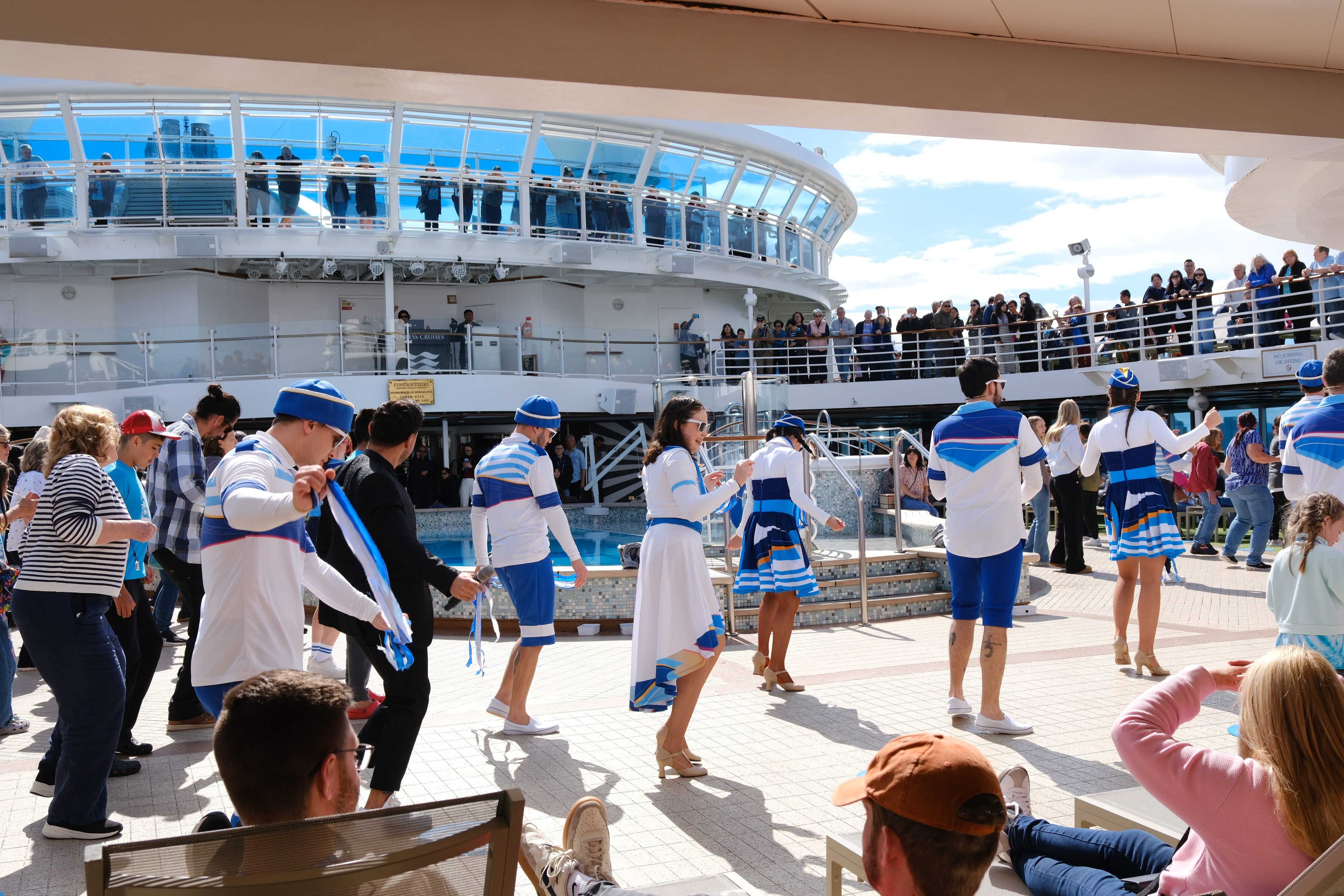 Sail-away party on the Emerald Princess pool deck — crew and passengers dancing together with the Skywalkers dome visible above