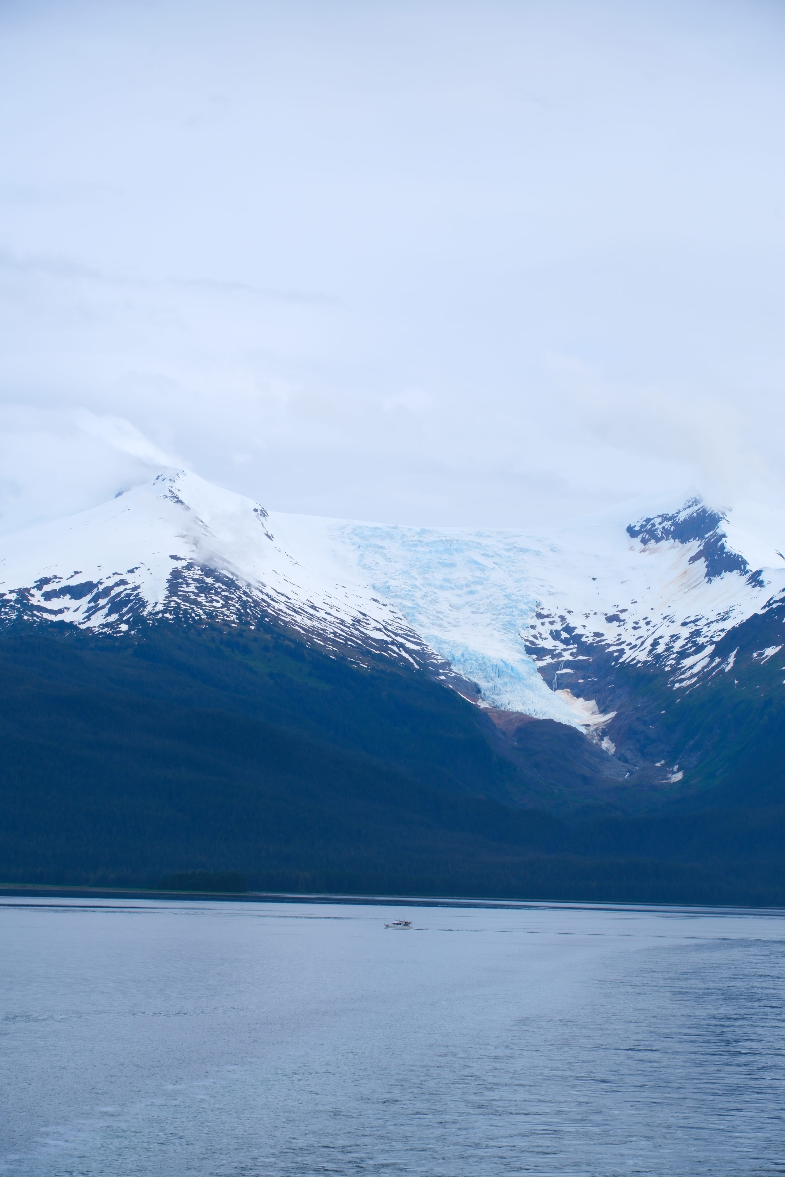 Glacier face on a mountainside with blue ice visible, water below