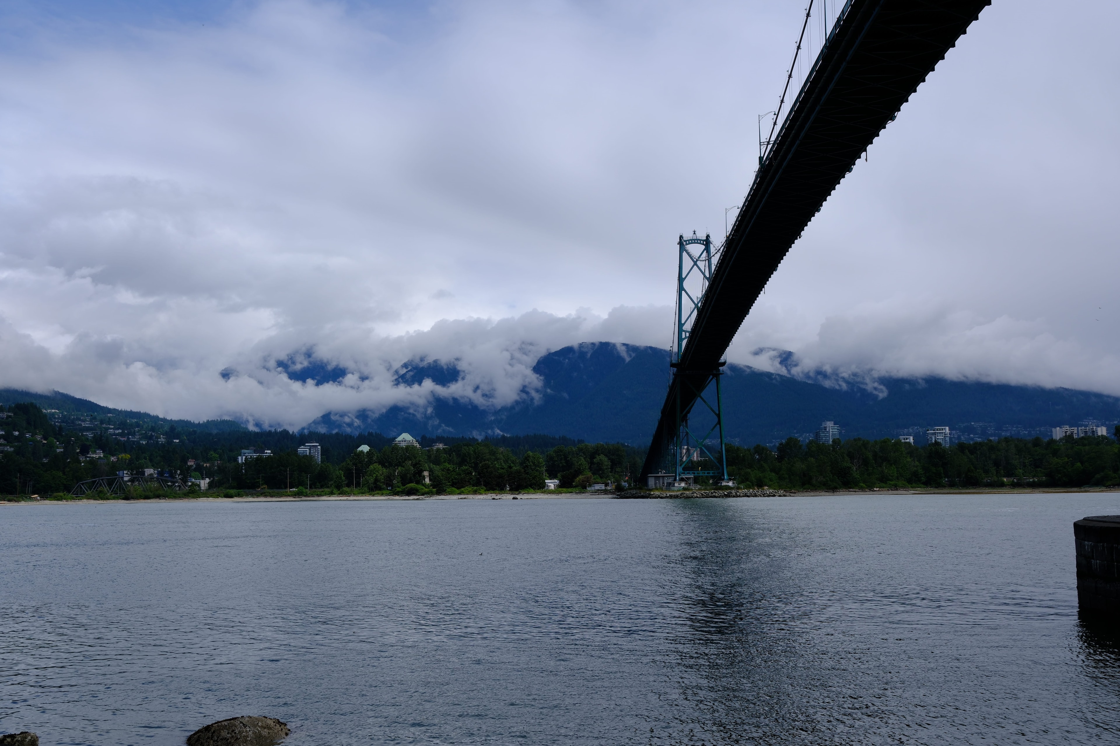 Lions Gate Bridge spanning Burrard Inlet with the North Shore mountains wrapped in low clouds behind it