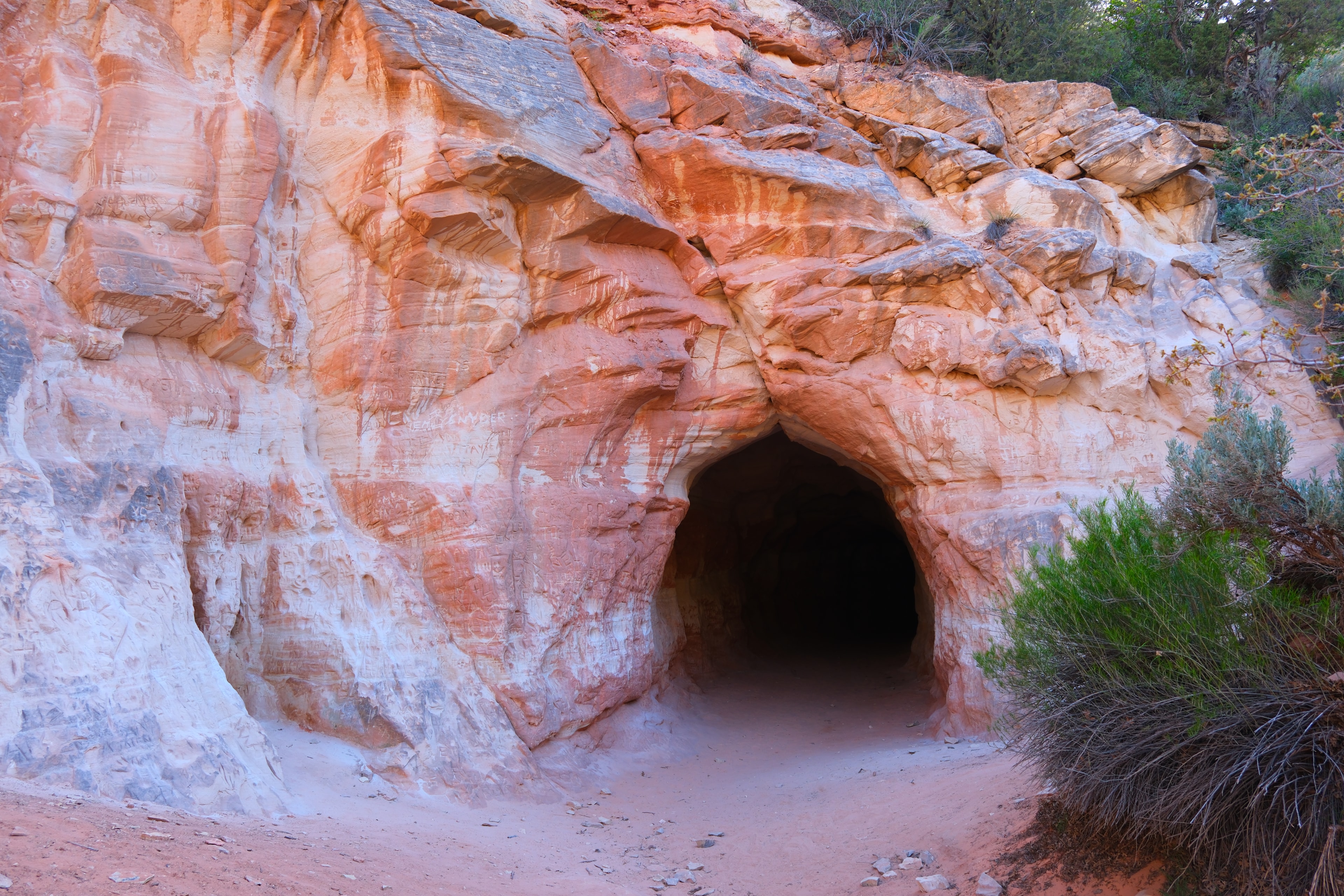 Clean wide exterior view of the Belly of the Dragon arched tunnel entrance in the orange sandstone cliff face Utah