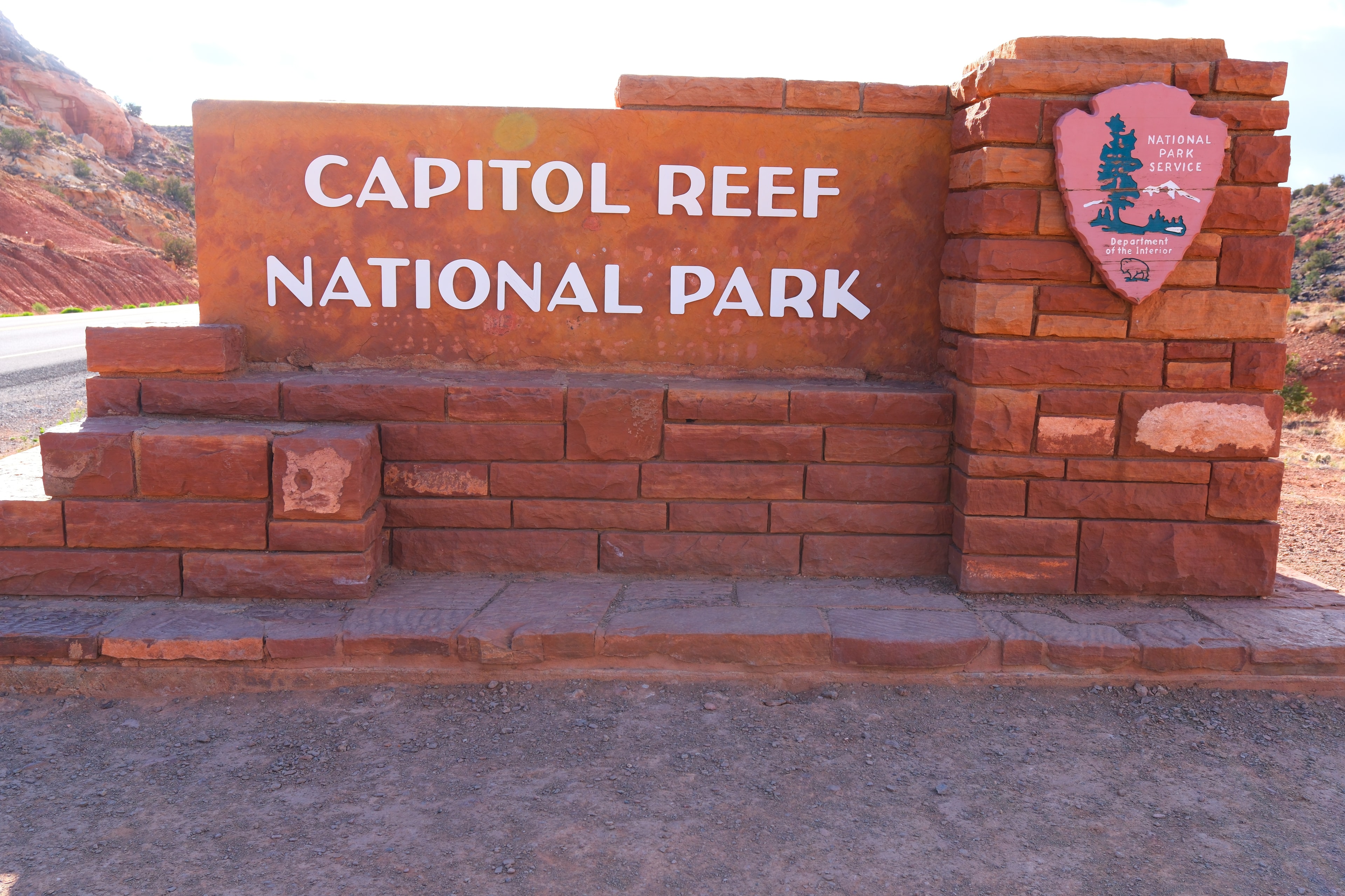 Capitol Reef National Park entrance sign red sandstone construction with NPS arrowhead badge at Capitol Reef National Park Utah