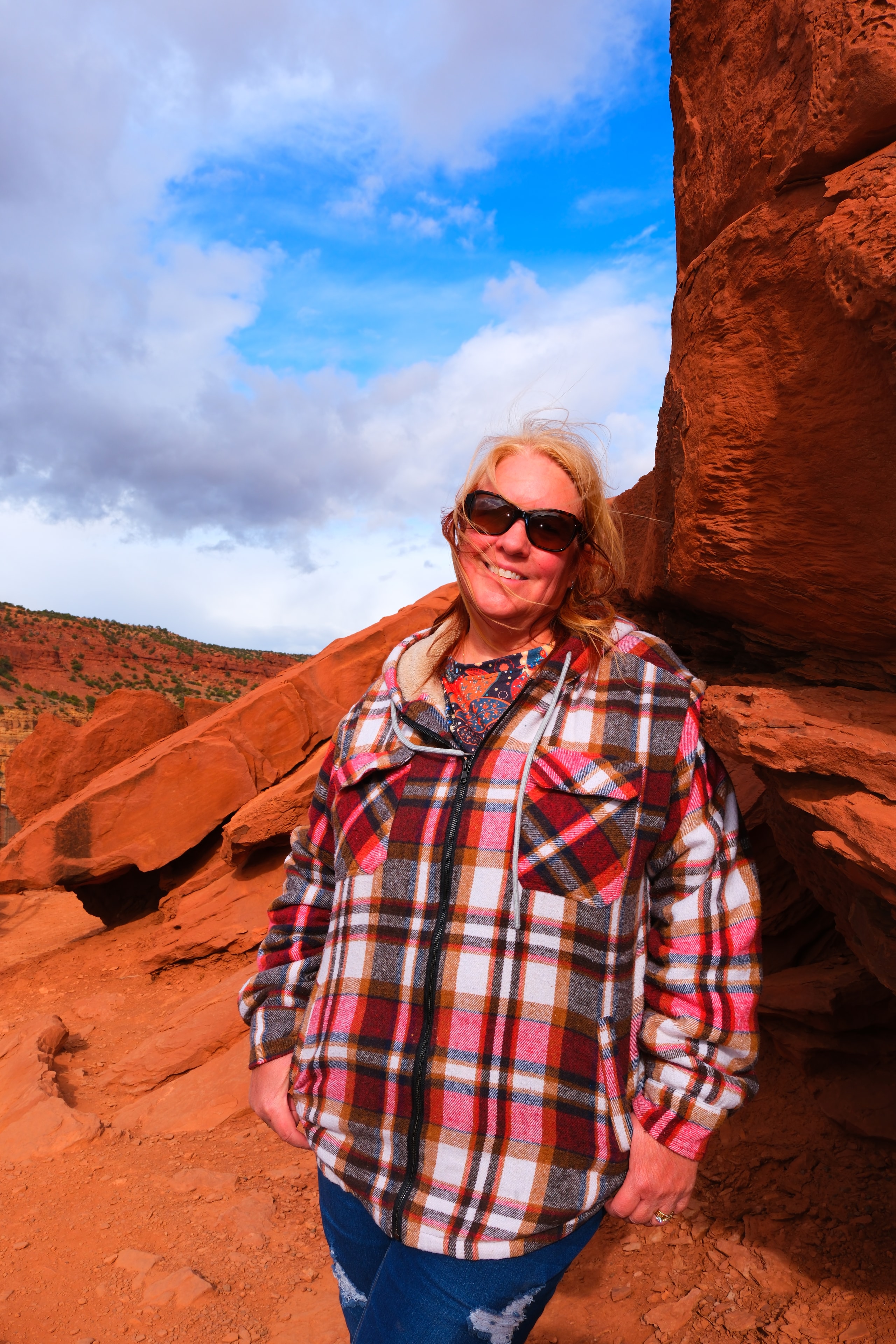 Tina at red rock overlook in plaid flannel with big smile and blue sky and canyon behind at Capitol Reef National Park Utah