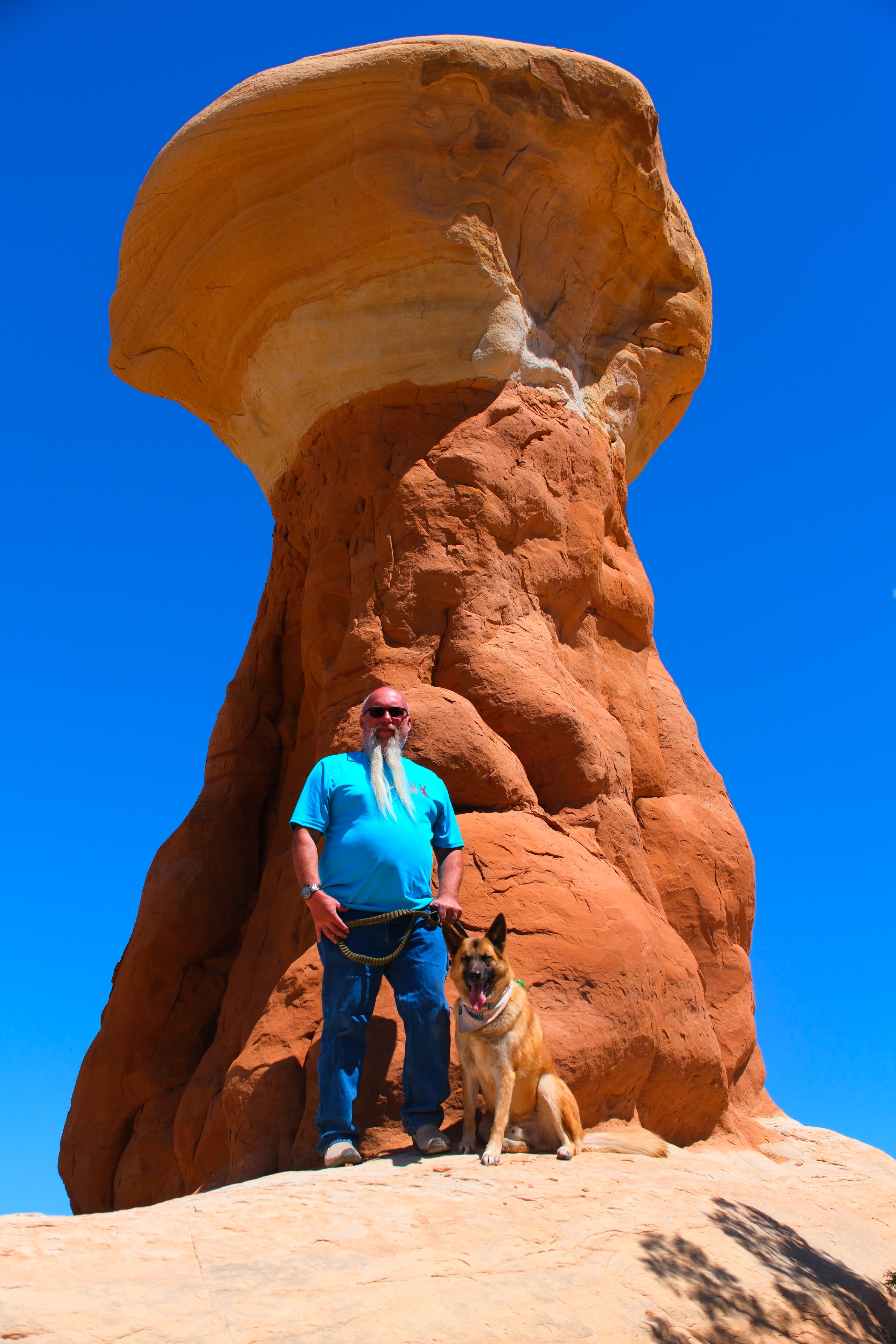 Joe and Zero at the base of a massive orange sandstone hoodoo mushroom cap at Devil's Garden Utah