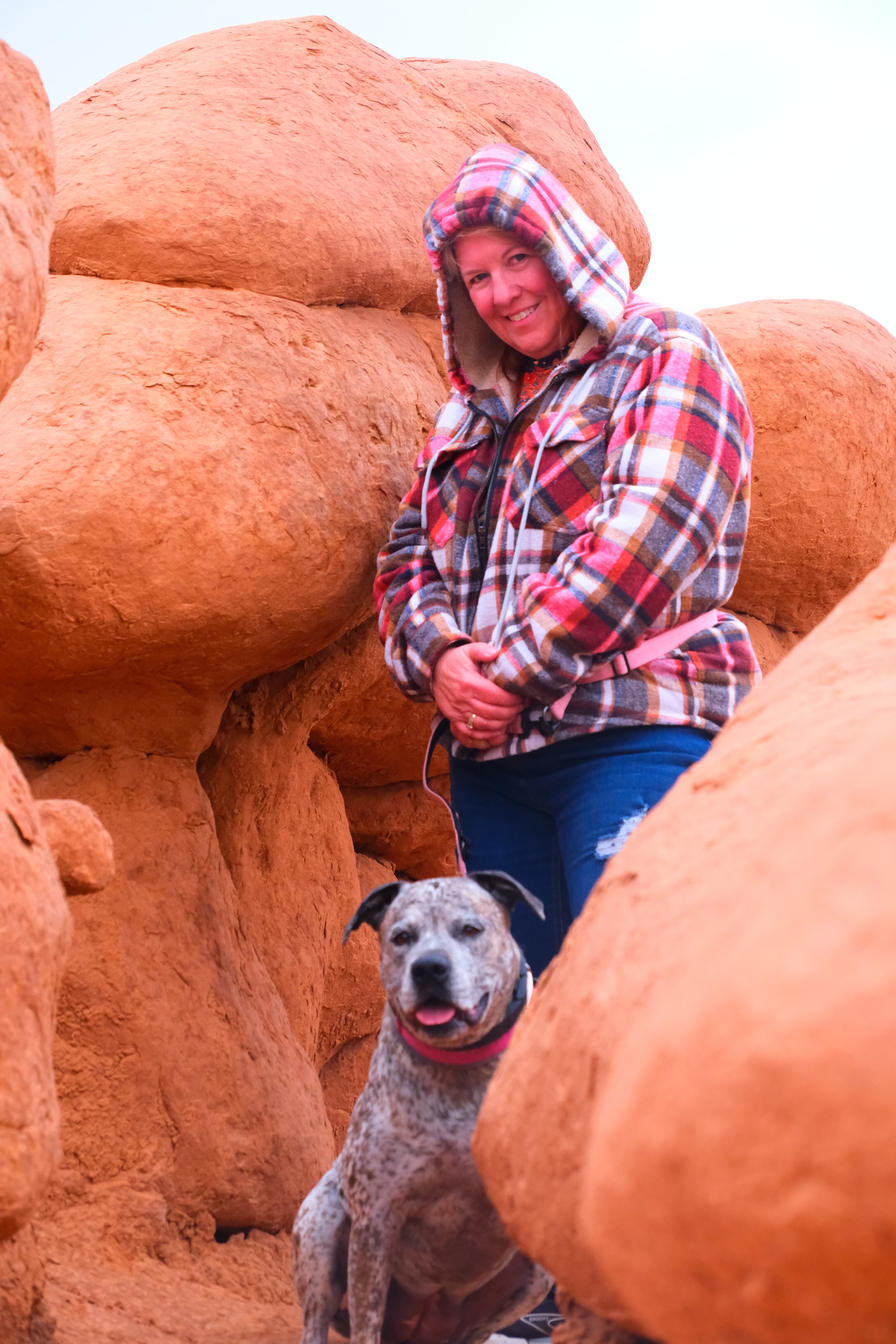 Tina smiling with Reecee framed by goblin boulders shot from below looking up at Goblin Valley State Park Utah