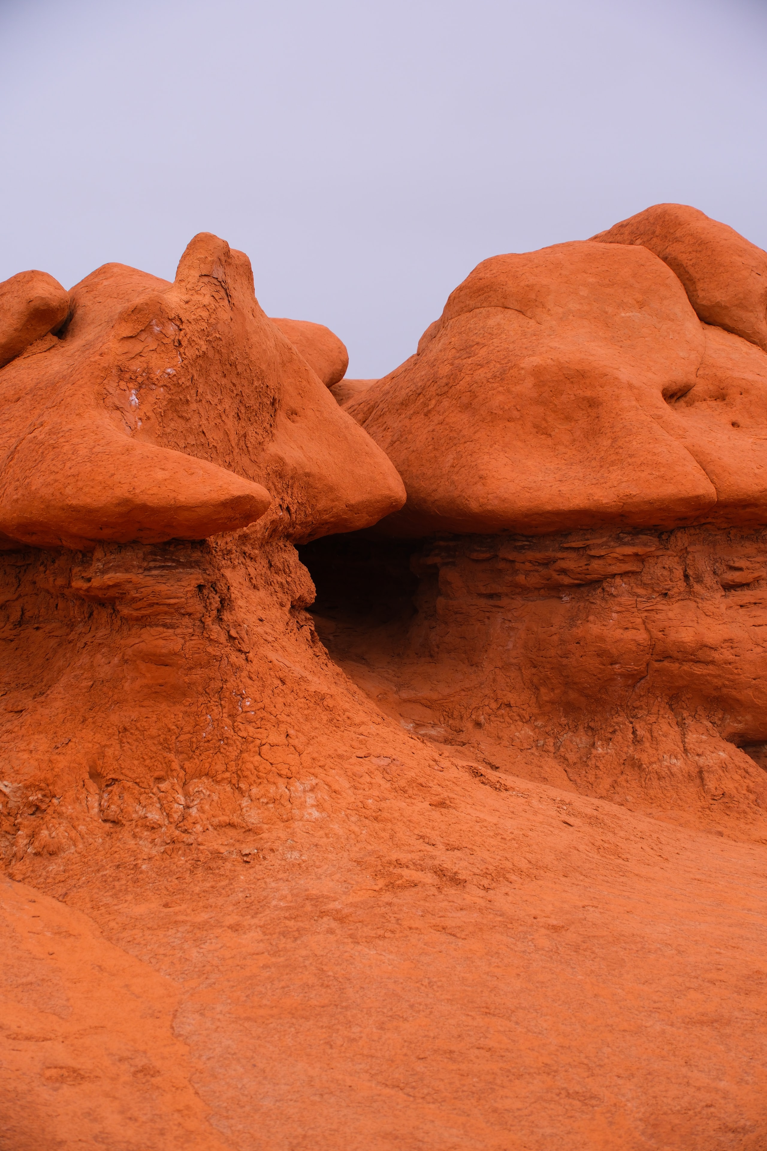 Large rounded goblin formation with deep crack splitting two sections warm orange tones closeup at Goblin Valley State Park Utah