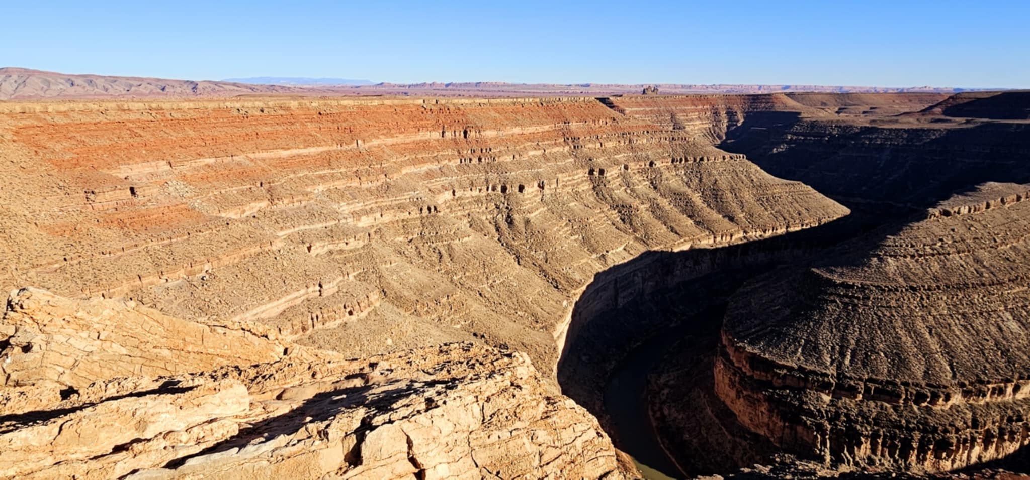 Panoramic view of dramatically layered sandstone canyon walls dropping to the San Juan River at Goosenecks State Park Utah