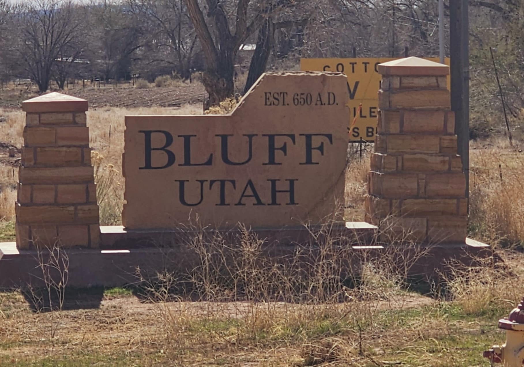 Bluff Utah welcome sign on sandstone monument reading Est 650 AD with bare cottonwood trees behind