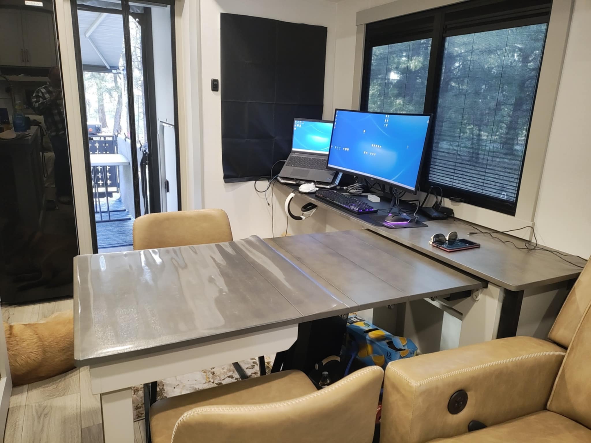 Joe's dual-monitor setup on the Brinkley Z3400 Dinesk — laptop, curved monitor, and RGB keyboard in the pines